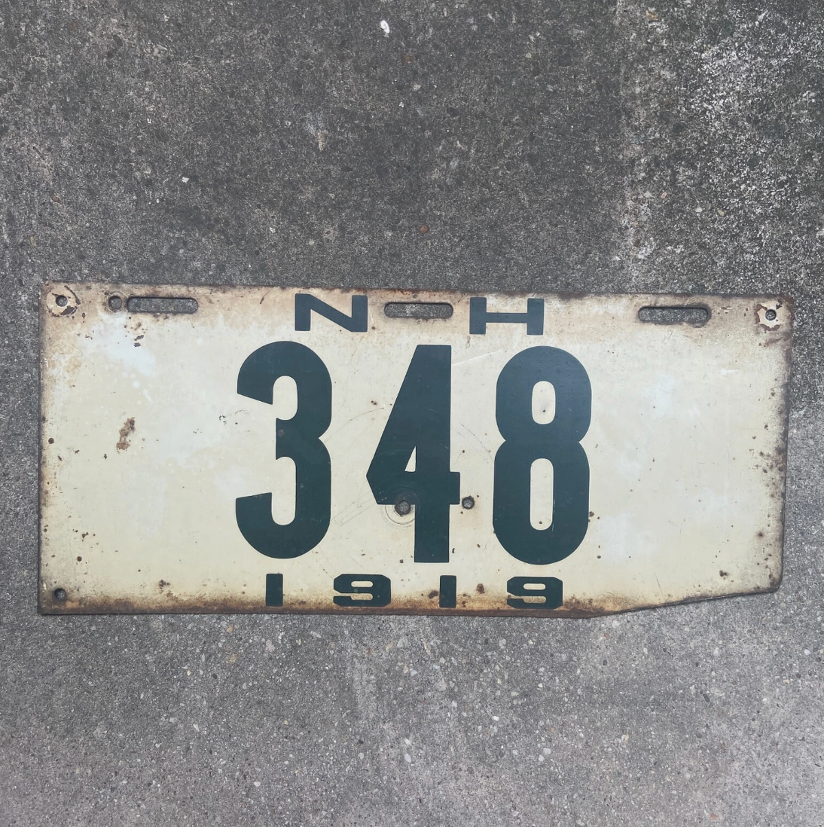 Vintage 1919 New Hampshire license plate with '348' on a concrete surface