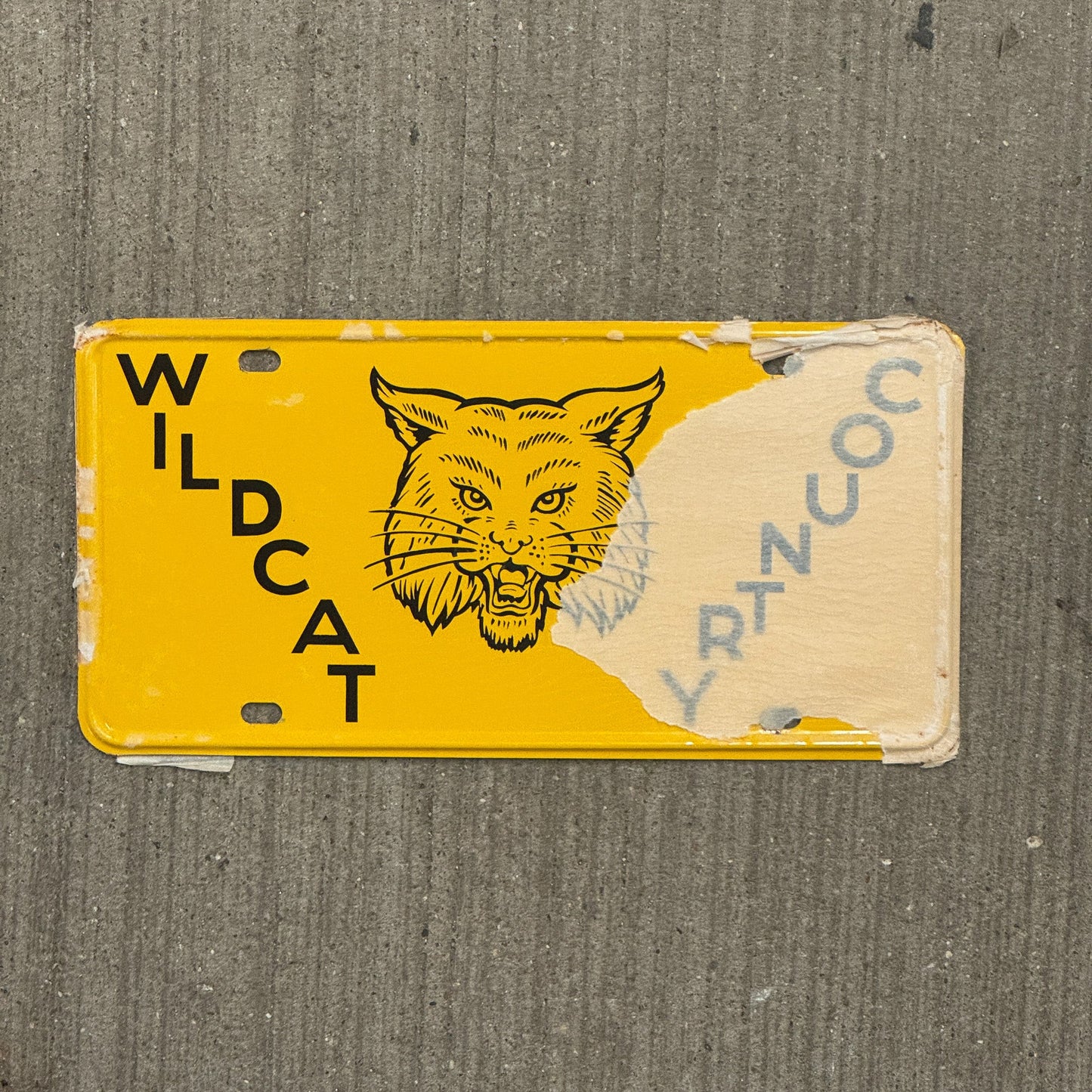 Photo of a 1950 Era Booster License Plate Auto Tag Garage Decor Vintage New Old Stock with Rice Paper Wildcat Country with original patina