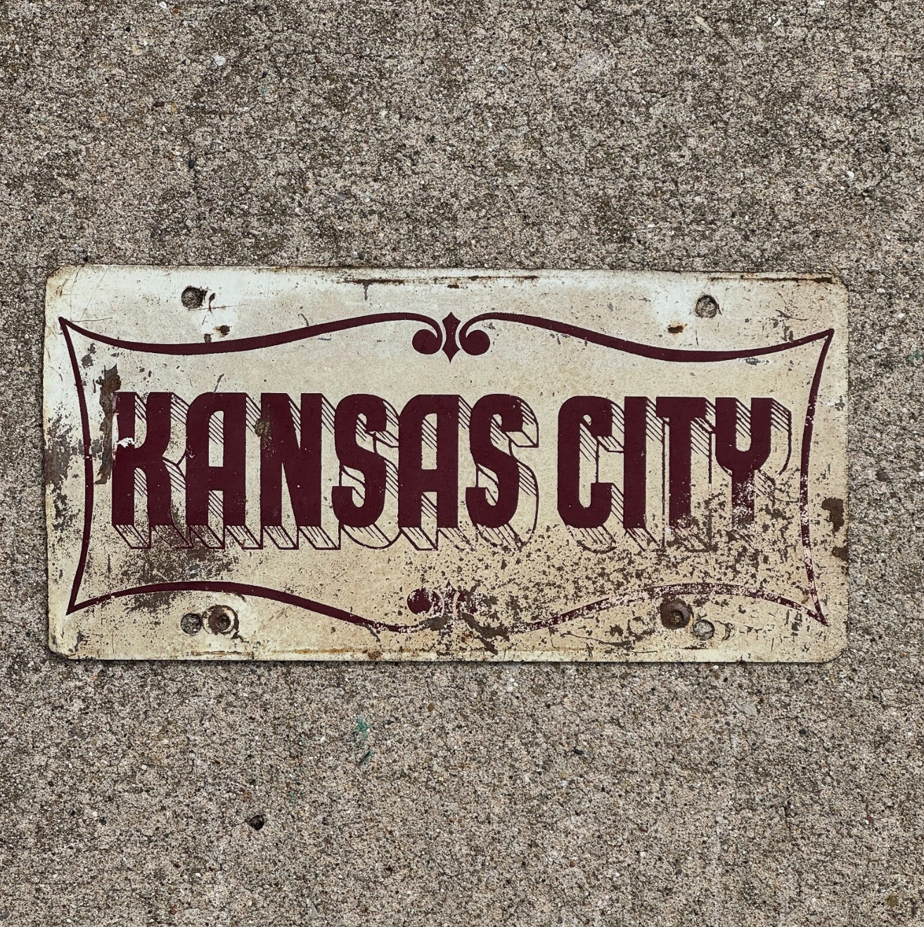 Photo of a 1950 Era Kansas City Missouri Booster License Plate Auto Tag Garage Decor Vintage Maroon Red White with original patina