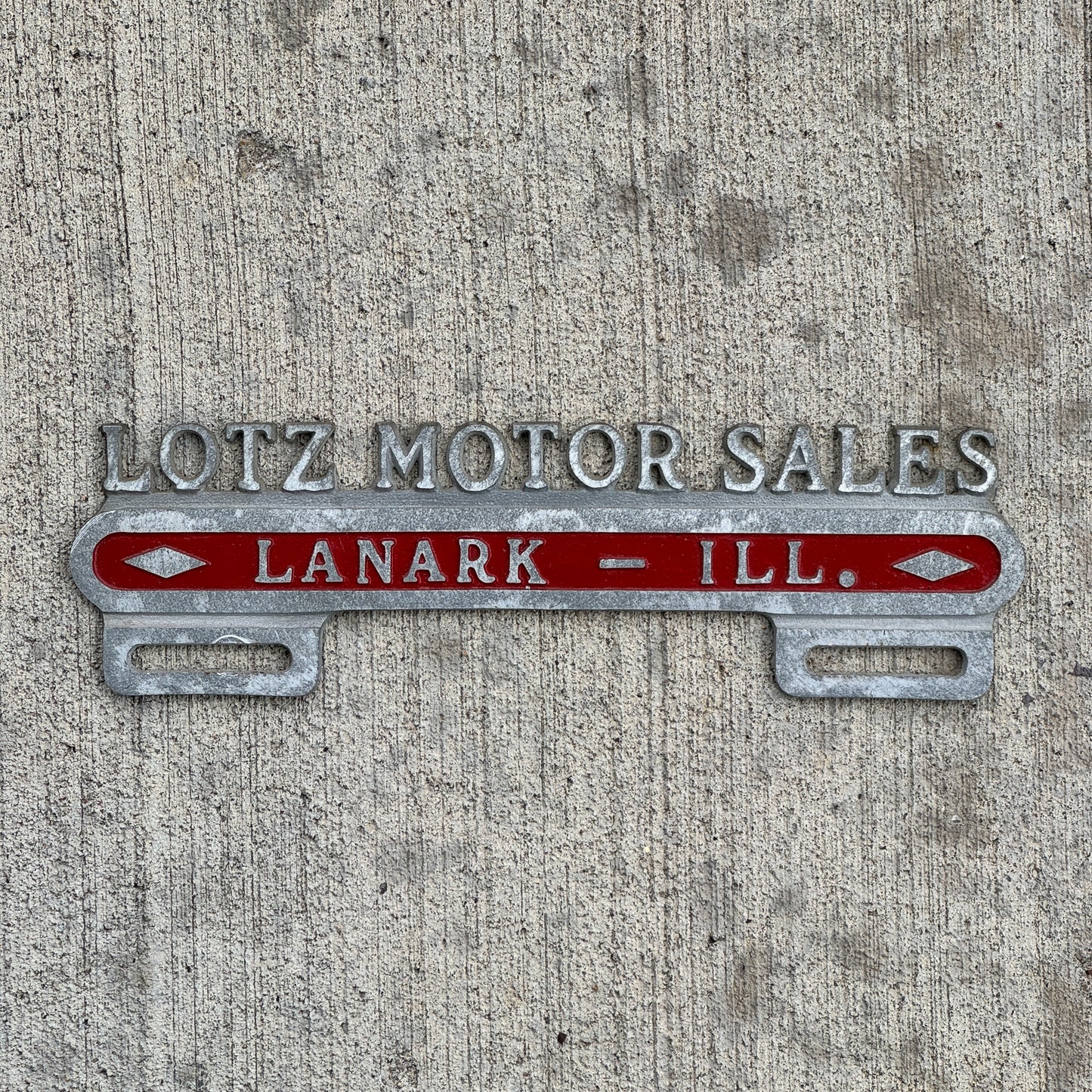 Photo of a 1950 Era Lotz Motor Sales Lanark Illinois License Plate Topper Auto Tag Garage Decor Vintage Cast Aluminum Buick Pontiac with original patina