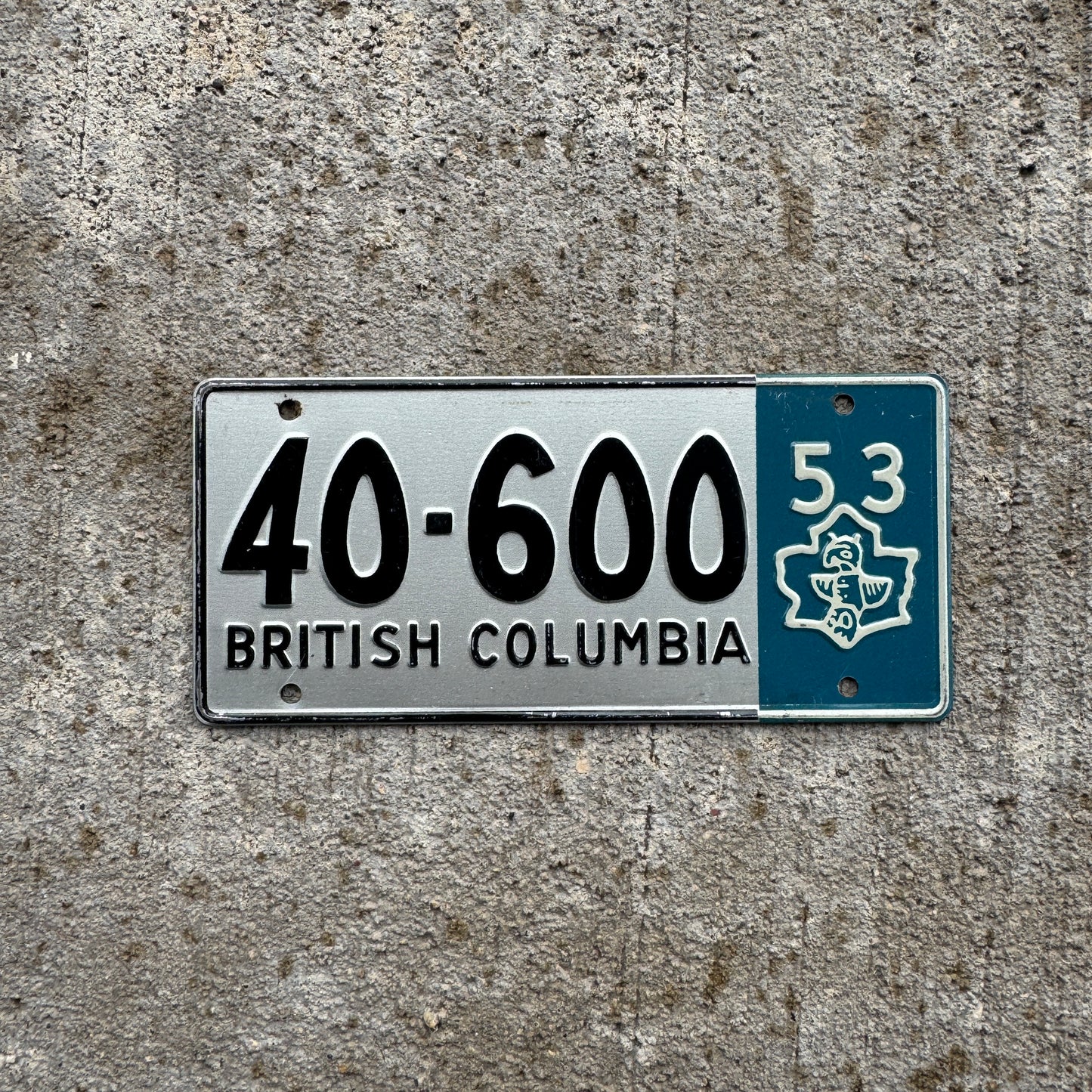 Photo of a 1953 British Columbia Wheaties Cereal Bike License Plate Auto Tag 40-600 on a concrete background