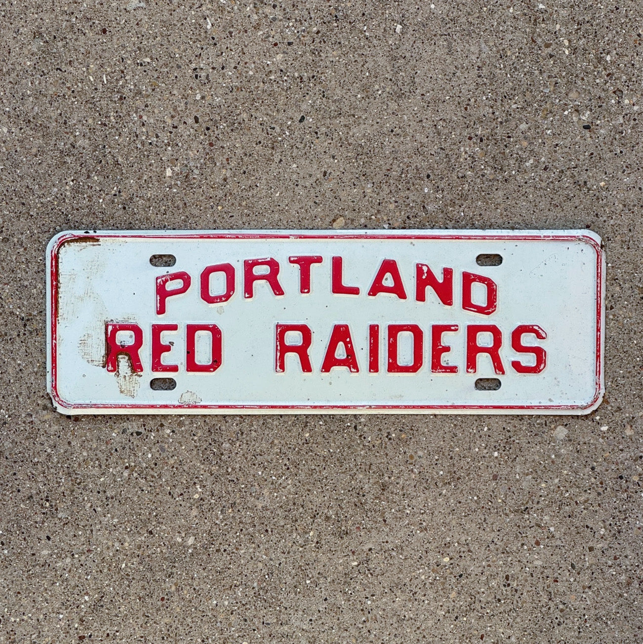 Photo of a 1960 Era Portland Michigan License Plate Topper Auto Tag Garage Decor Vintage Red Raiders with original patina
