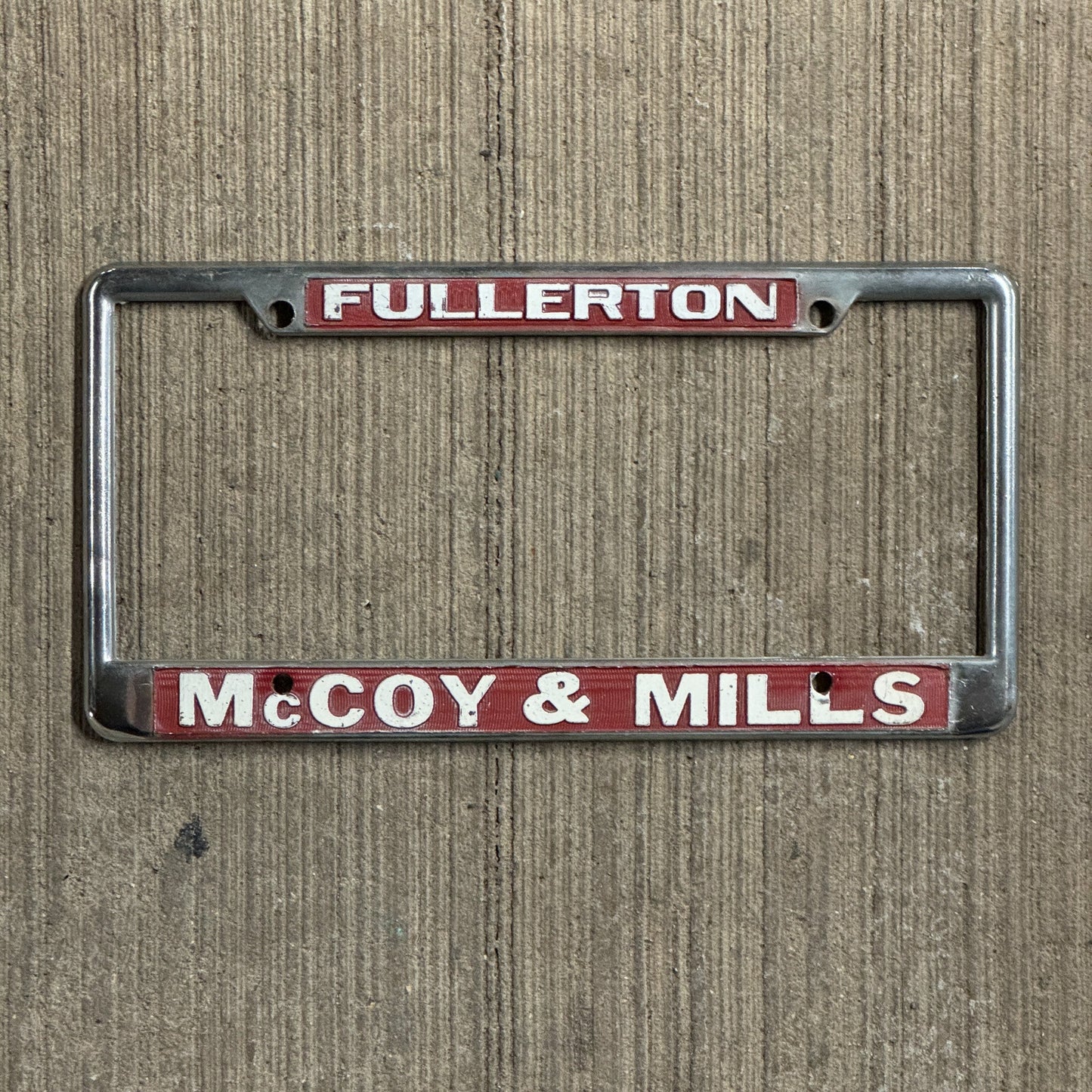 Photo of a 1970 Era California License Plate Frame Auto Tag 1 Vintage Garage Fullerton Metal McCoy & Mills Ford Dealer with original patina