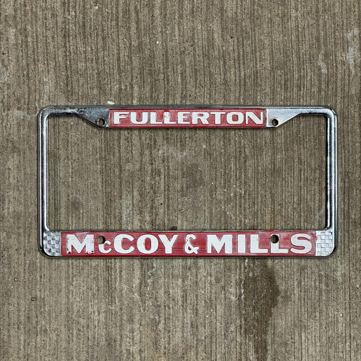 Photo of a 1970 Era California License Plate Frame Auto Tag 2 Vintage Garage Fullerton Metal McCoy & Mills Ford Dealer with original patina