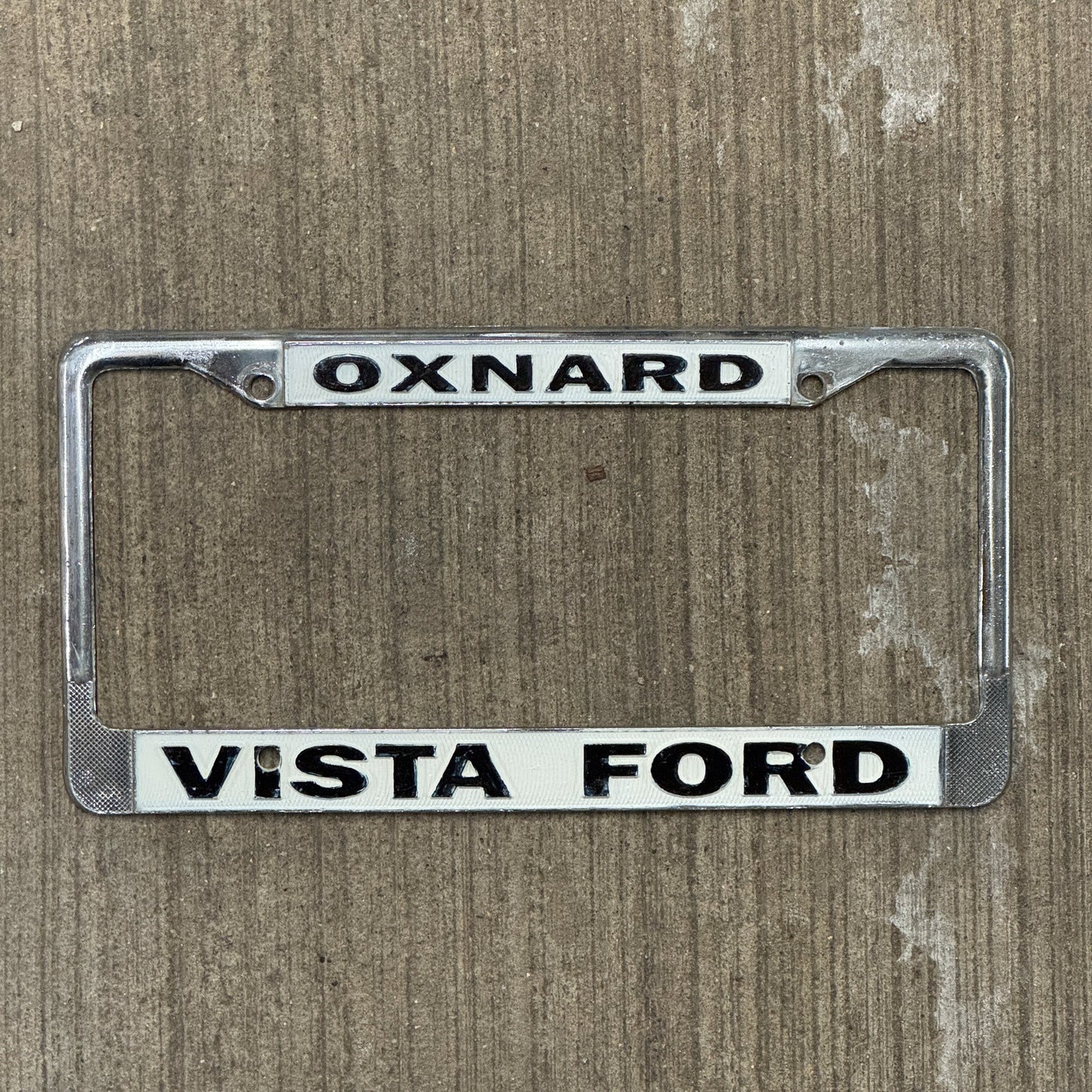 Photo of a 1970 Era California License Plate Frame Auto Tag Garage Decor Vintage Oxnard Metal Vista Ford with original patina