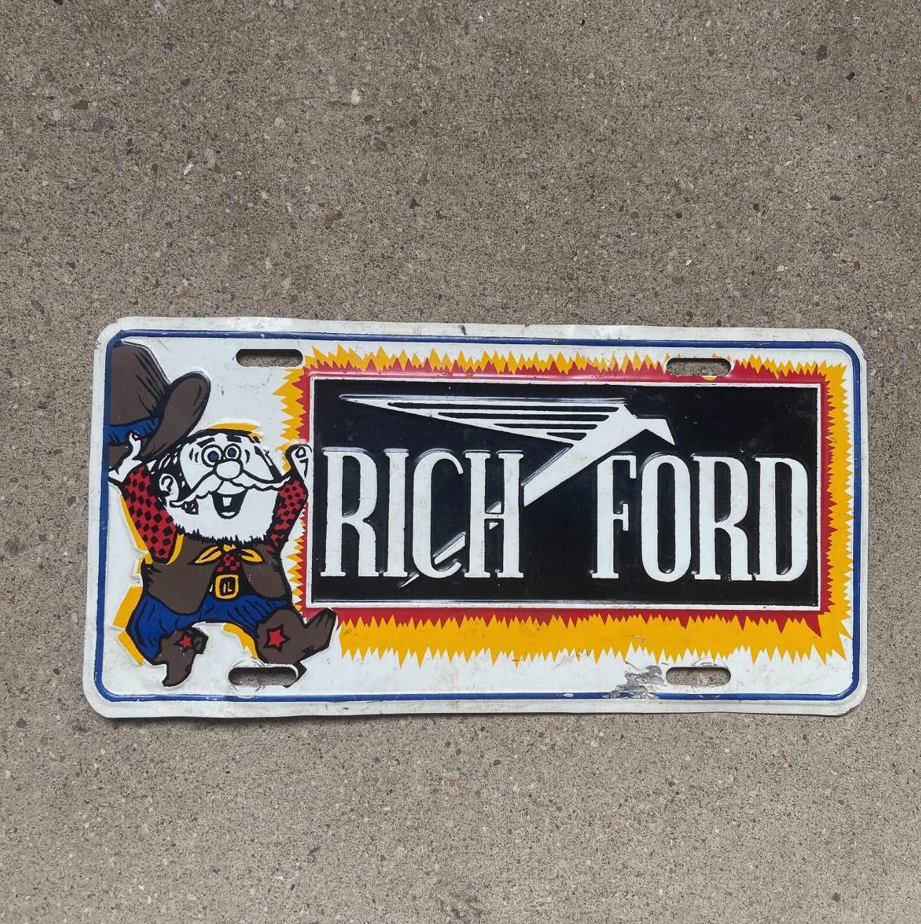 Photo of a 1970 Era Rich Ford New Mexico Booster License Plate Auto Tag Garage Decor Vintage Dealer Albuquerque NM with original patina