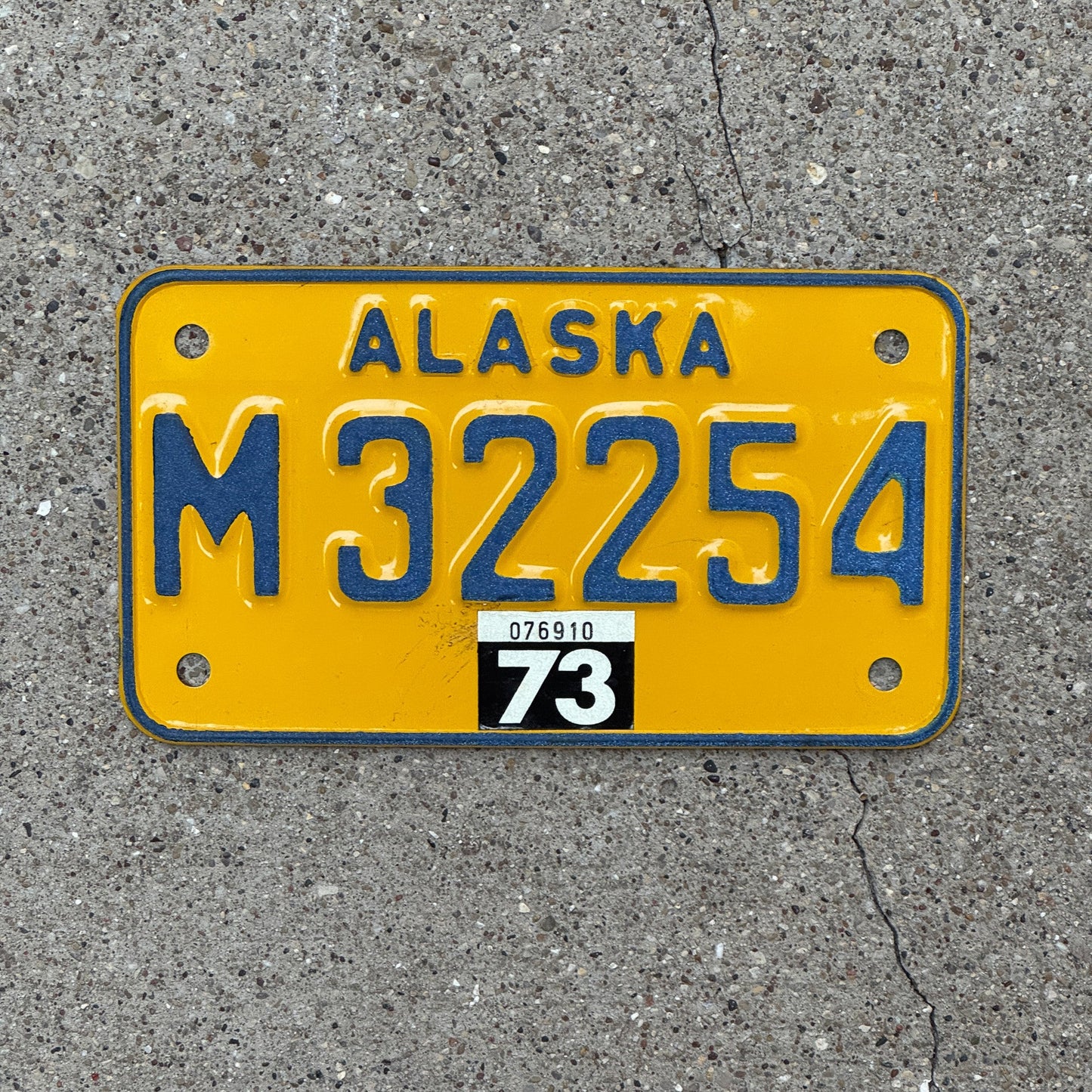 Photo of a 1973 Alaska Motorcycle License Plate Auto Tag Garage Decor Vintage Natural 1973 Sticker M 32254 with original patina