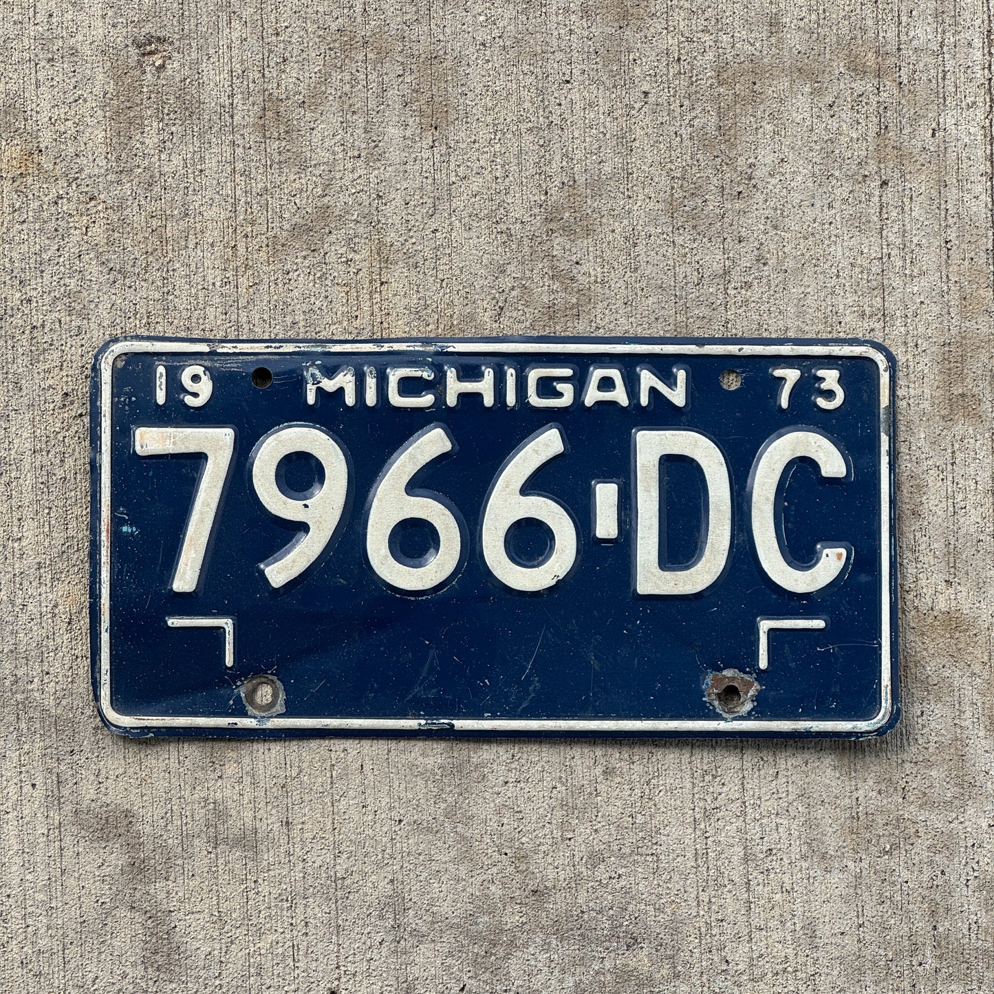 Photo of a 1973 Michigan Commercial License Plate Auto Tag Garage Decor Vintage 7966 DC with original patina