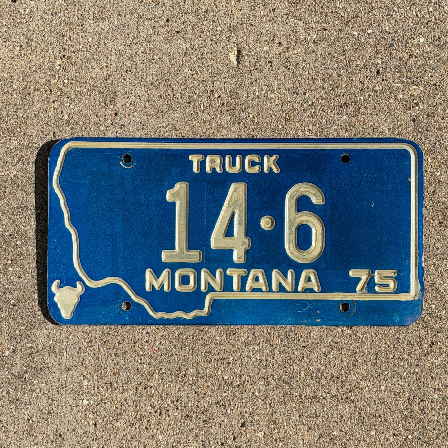 Photo of a 1975 Montana Truck License Plate Auto Tag Garage Decor Vintage State Shape Low Number Two Digit Custer County 14 6 with original patina