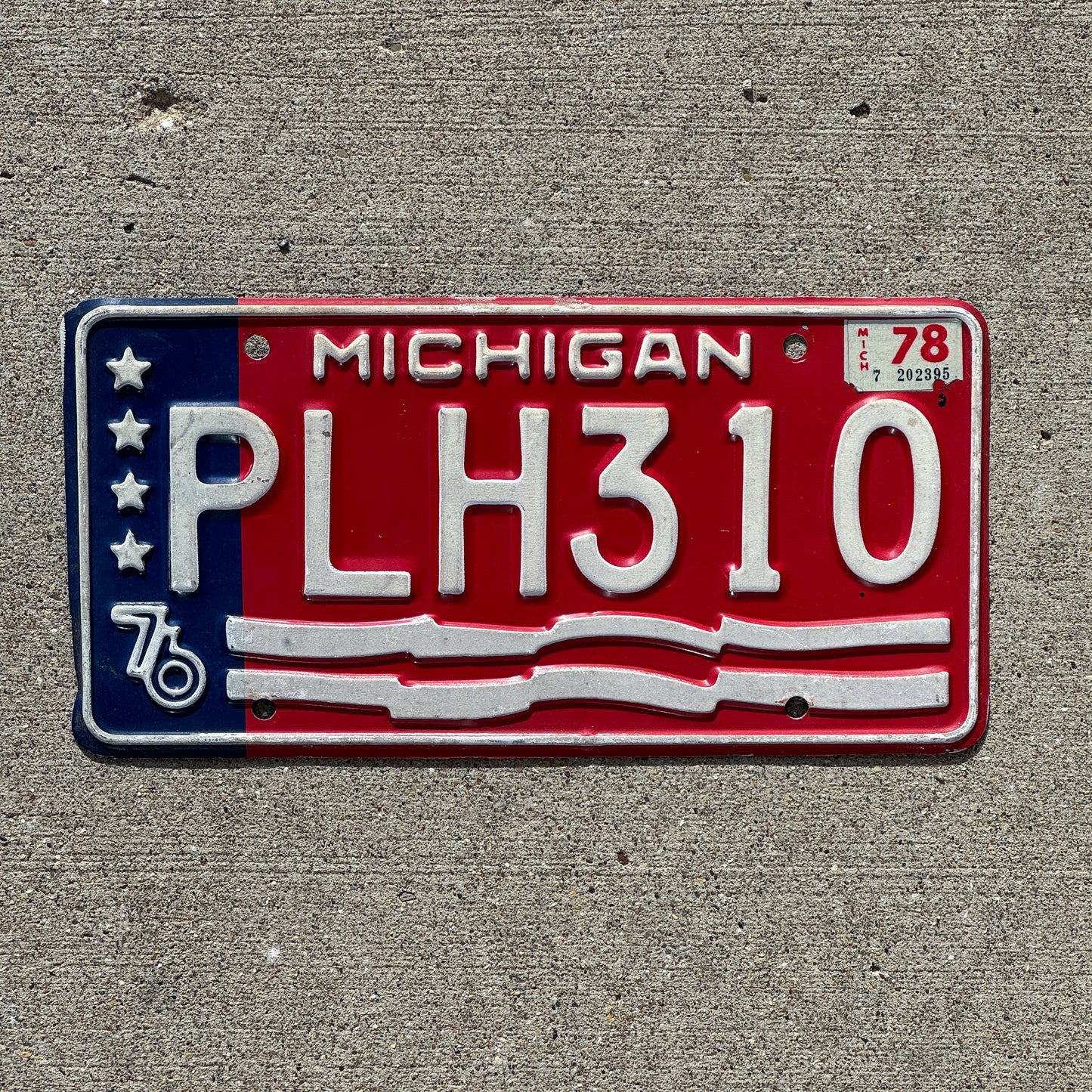 Photo of a 1976 1978 Michigan License Plate Auto Tag Garage Decor Vintage American Flag Bicentennial PLH 310 with original patina