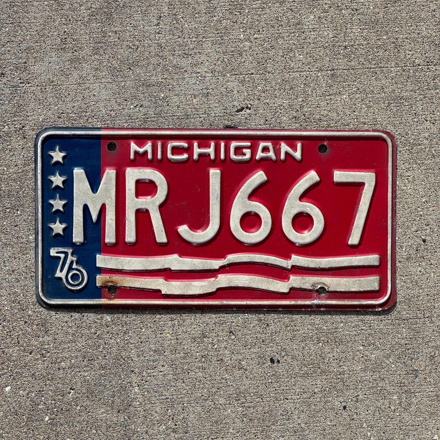 Photo of a 1976 Michigan License Plate Auto Tag Garage Decor Vintage American Flag Bicentennial MRJ 667 with original patina