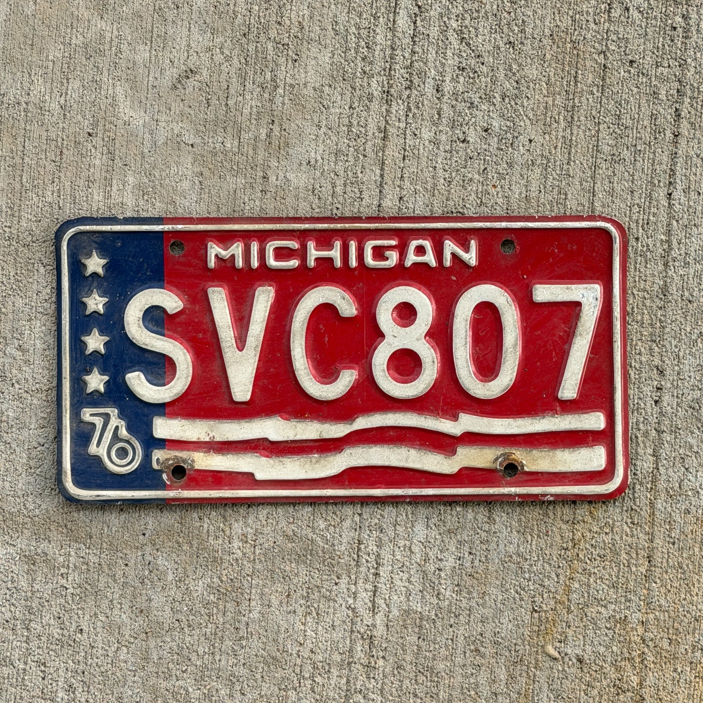 Photo of a 1976 Michigan License Plate Auto Tag Garage Decor Vintage Bicentennial SVC 807 with original patina