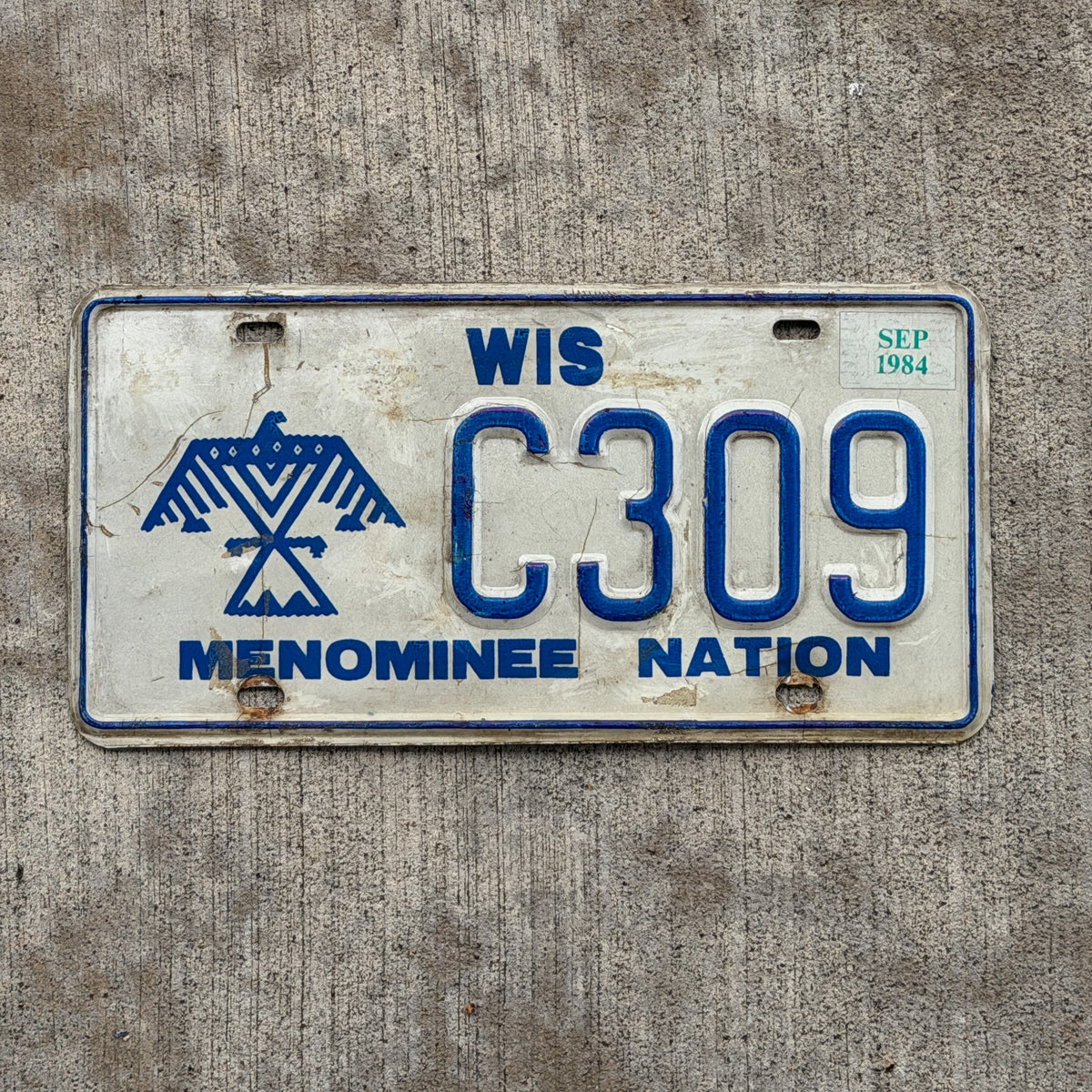 Photo of a 1980 1984 Wisconsin Graphic / Specialty License Plate Auto Tag Garage Decor Vintage Native American Indian Tribe Menominee Nation C 309 with original patina