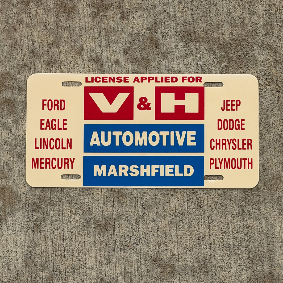 Photo of a 1980 Era Marshfield Wisconsin Booster License Plate Auto Tag Garage Decor Vintage V & H Automotive Plastic with original patina