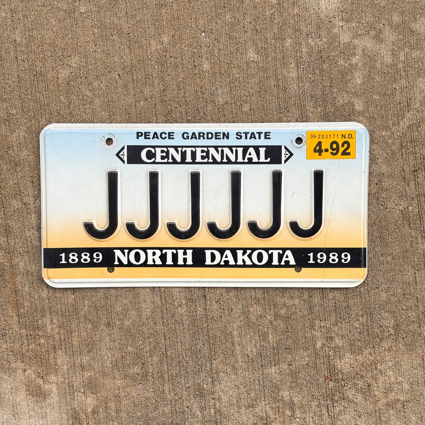Photo of a 1987 1992 North Dakota Vanity License Plate Auto Tag Garage Decor Vintage Centennial Repeat Repeating JJJJJJ with original patina