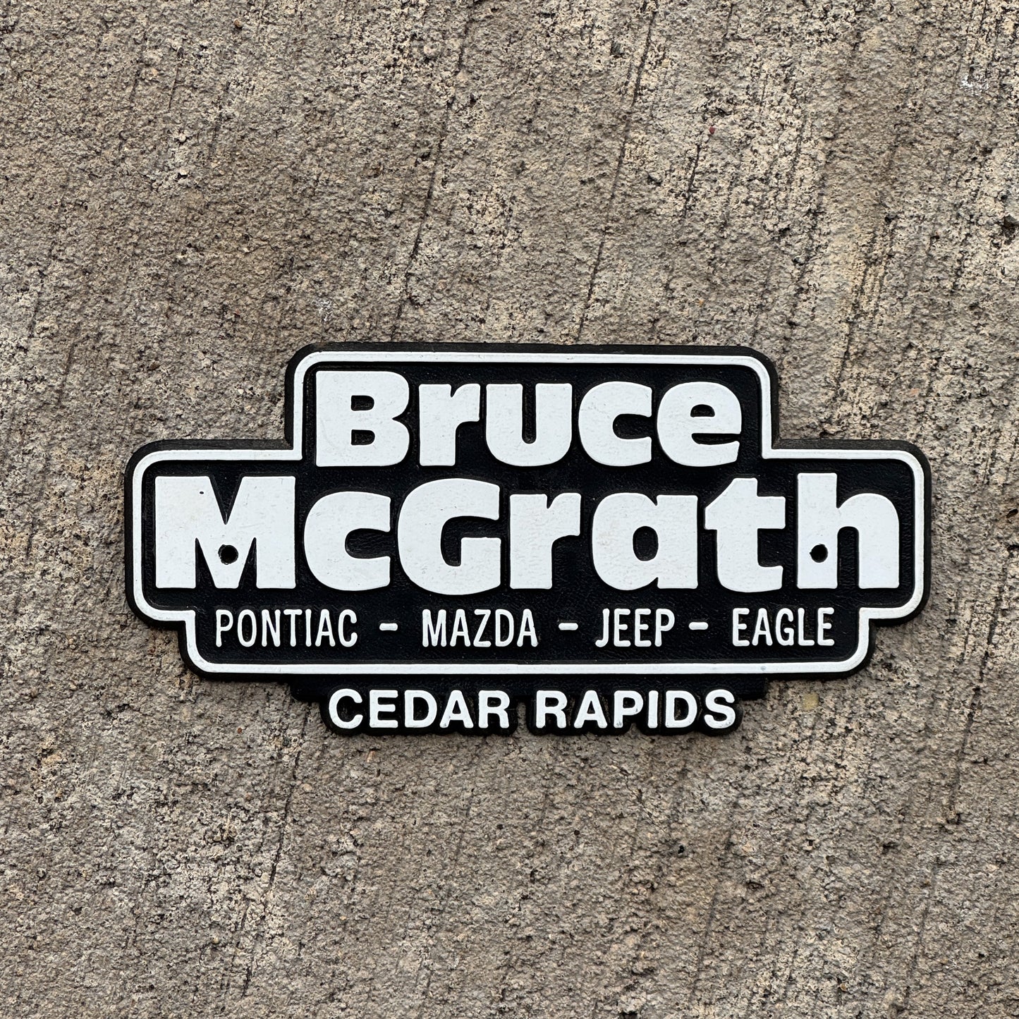 Photo of a 1990 Era Bruce McGrath Cedar Rapids Iowa Dealer Badge Emblem Auto Tag Garage Decor Vintage Pontiac Mazda Plastic Dealership with original patina