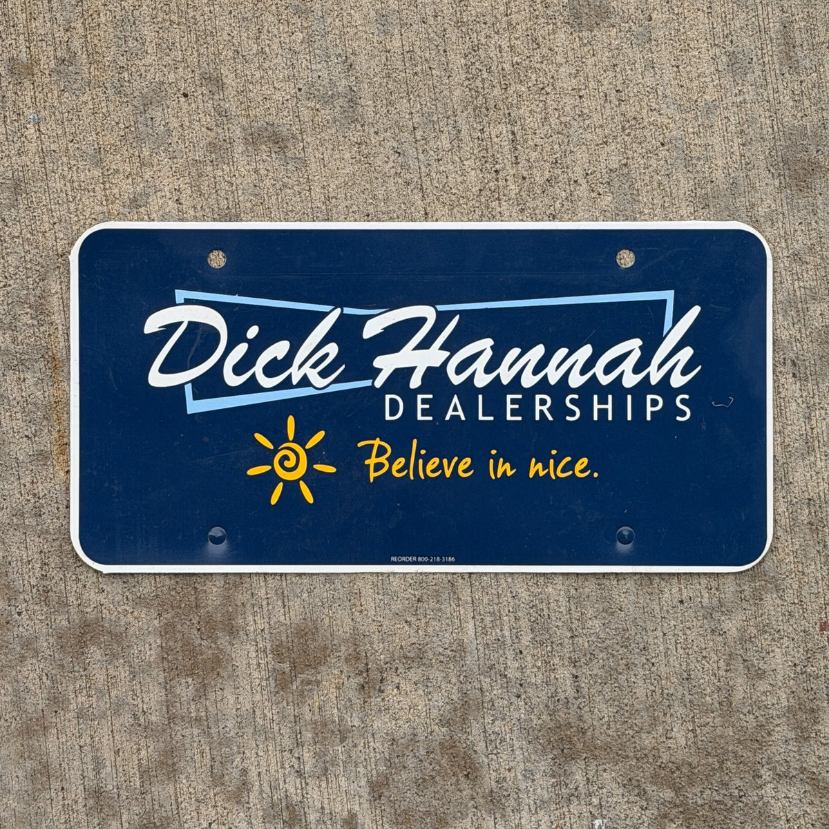 Photo of a 2000 Era Dick Hannah Dealerships Booster License Plate Auto Tag Garage Decor Vintage Plastic with original patina