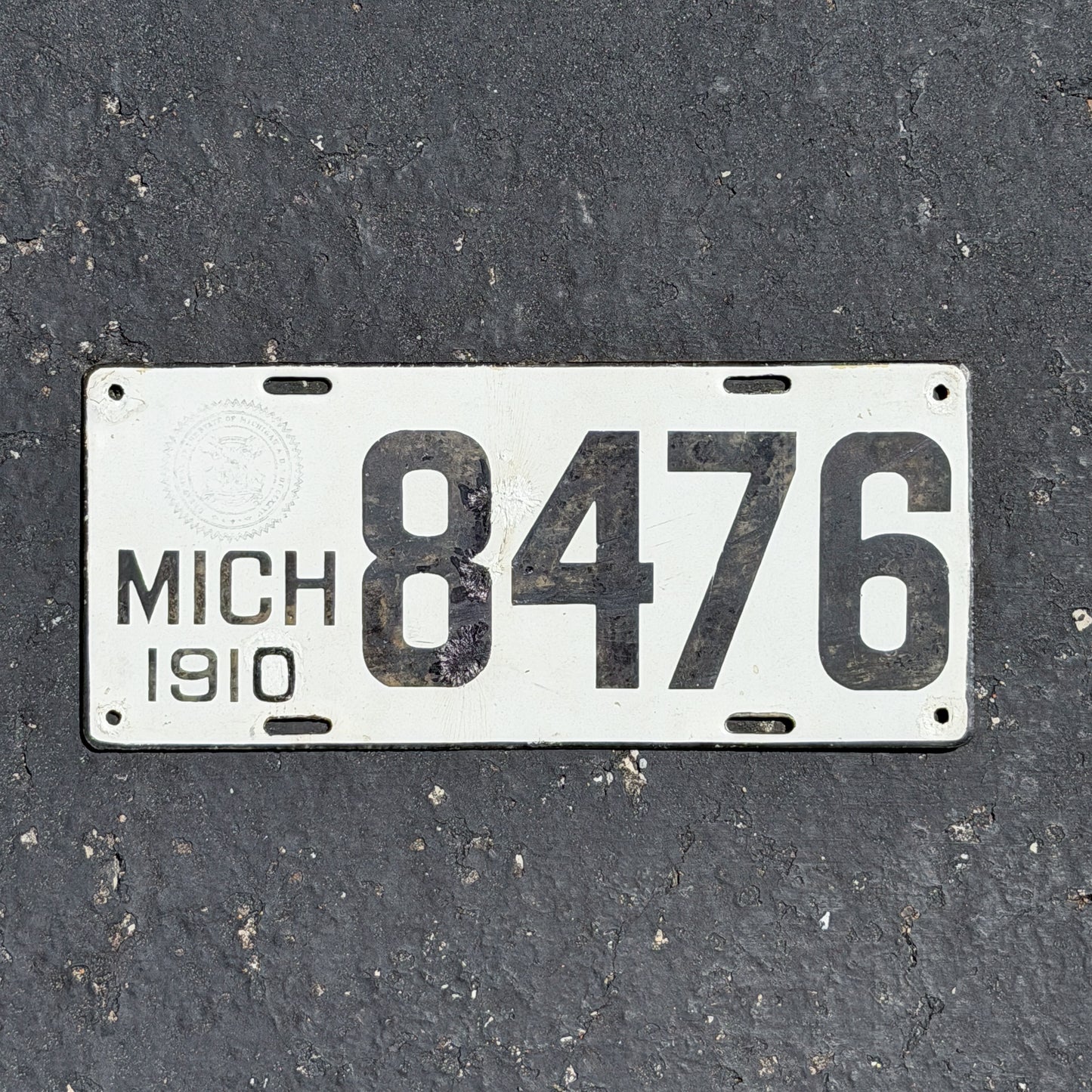 Photo of a 1910 Michigan Porcelain License Plate Auto Tag Garage Decor Vintage Low Number Four Digit 8476 with original patina