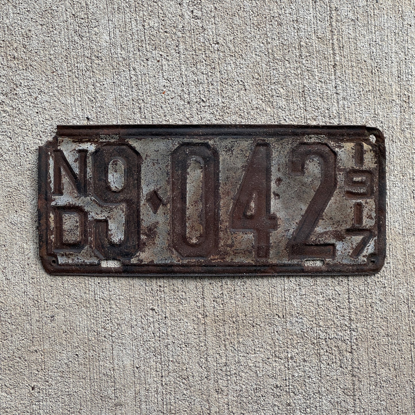 Photo of a 1917 North Dakota License Plate Auto Tag Garage Decor Vintage Four Digit Low Number 9042 with original patina