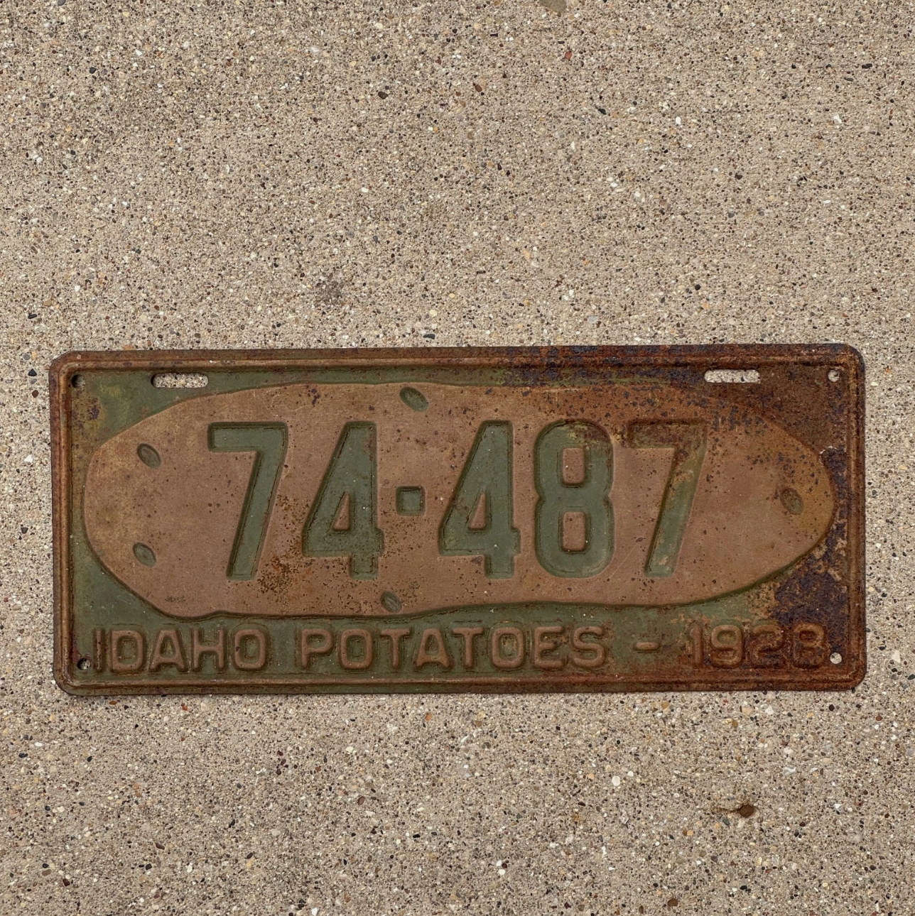 1928 Idaho potato license plate with numbers 74-487 on a concrete surface