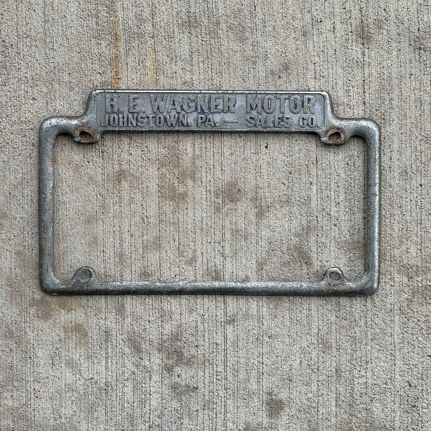 Photo of a 1940 Era H E Wagner Motor Co. Johnstown Pennsylvania License Plate Frame Auto Tag Garage Decor Vintage Dealer Dodge Plymouth Chrysler with original patina