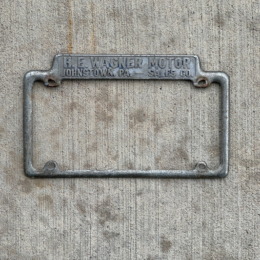 Photo of a 1940 Era H E Wagner Motor Co. Johnstown Pennsylvania License Plate Frame Auto Tag Garage Decor Vintage Dealer Dodge Plymouth Chrysler with original patina