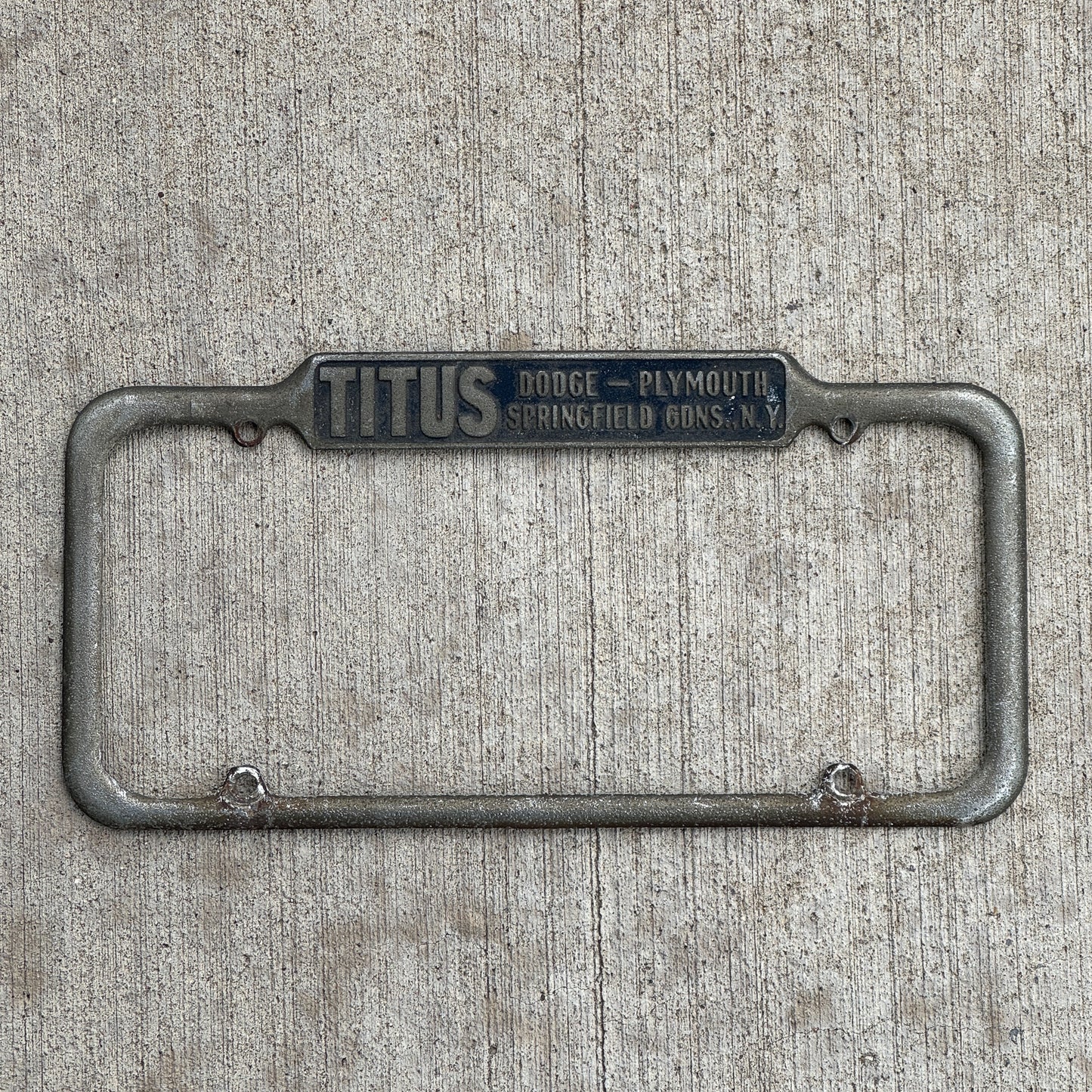Photo of a 1940 Era Titus Springfield Gardens New York License Plate Frame Auto Tag Garage Decor Vintage Dodge Plymouth Dealer with original patina