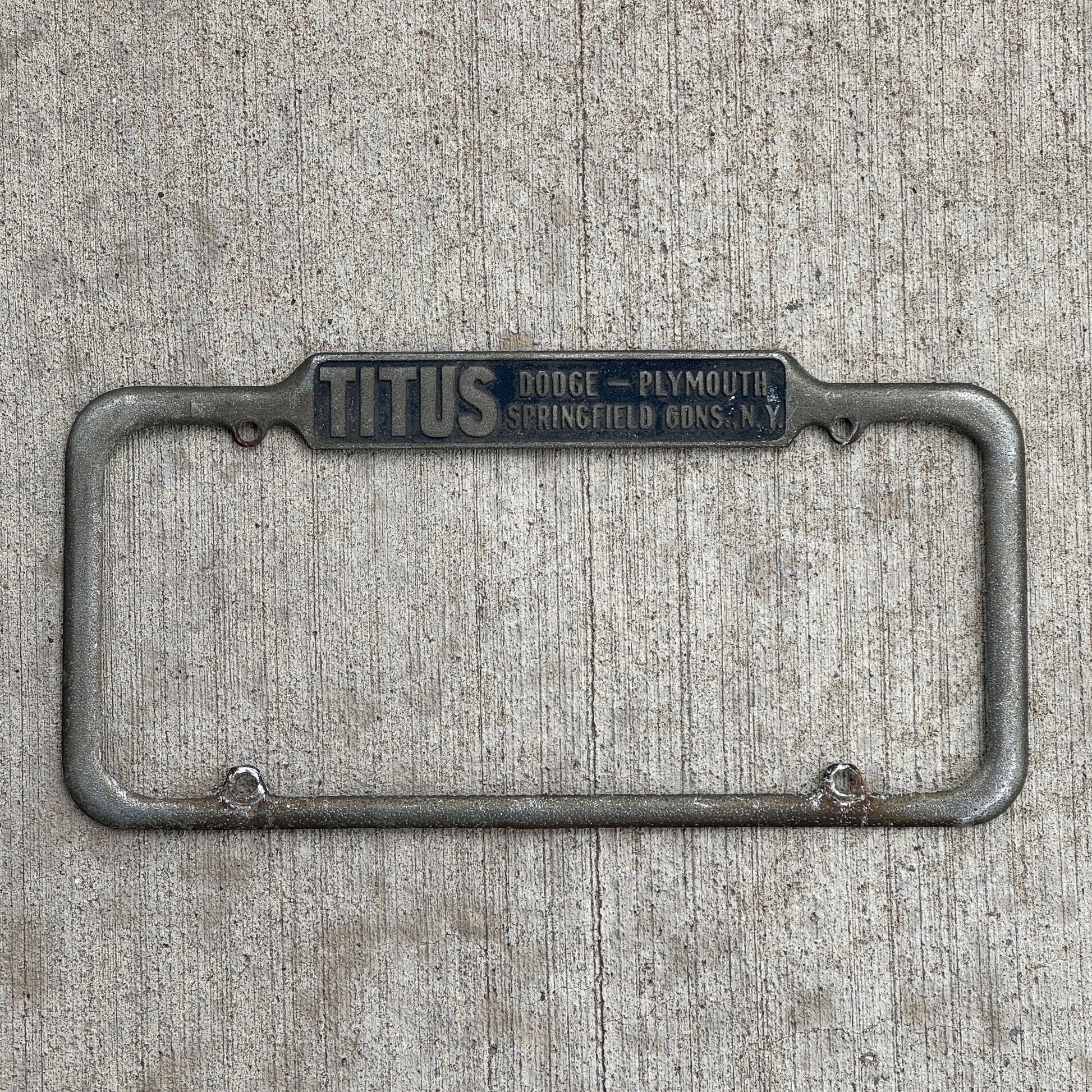Photo of a 1940 Era Titus Springfield Gardens New York License Plate Frame Auto Tag Garage Decor Vintage Dodge Plymouth Dealer with original patina