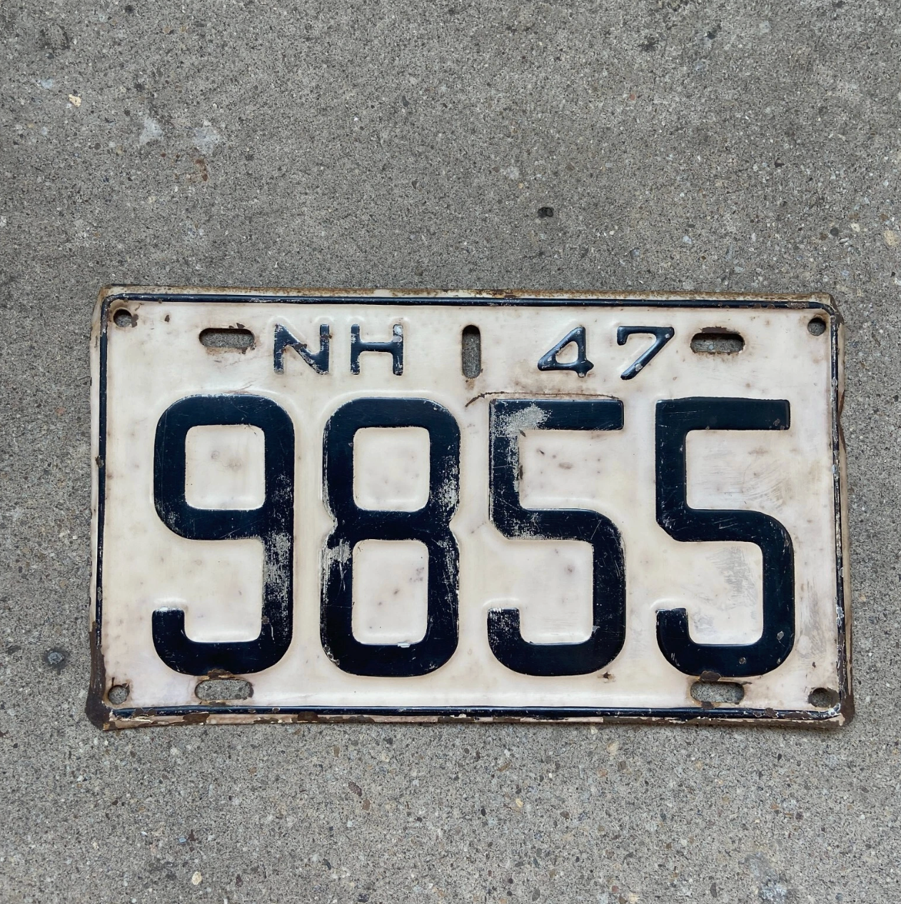 Vintage 1947 New Hampshire license plate with registration number '9855' on a concrete surface