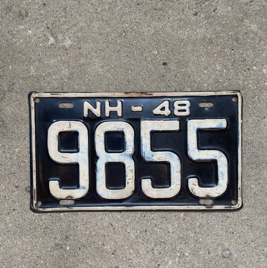Vintage 1948 New Hampshire license plate with registration number '9855' on a concrete surface