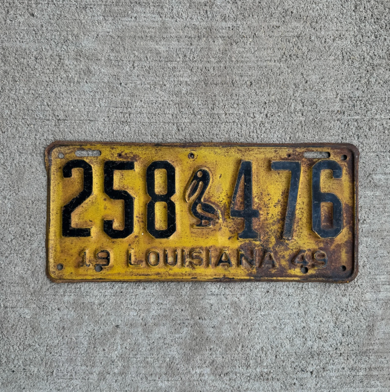 Vintage Louisiana license plate with iconic pelican graphic and the number 258 476 on a concrete background.