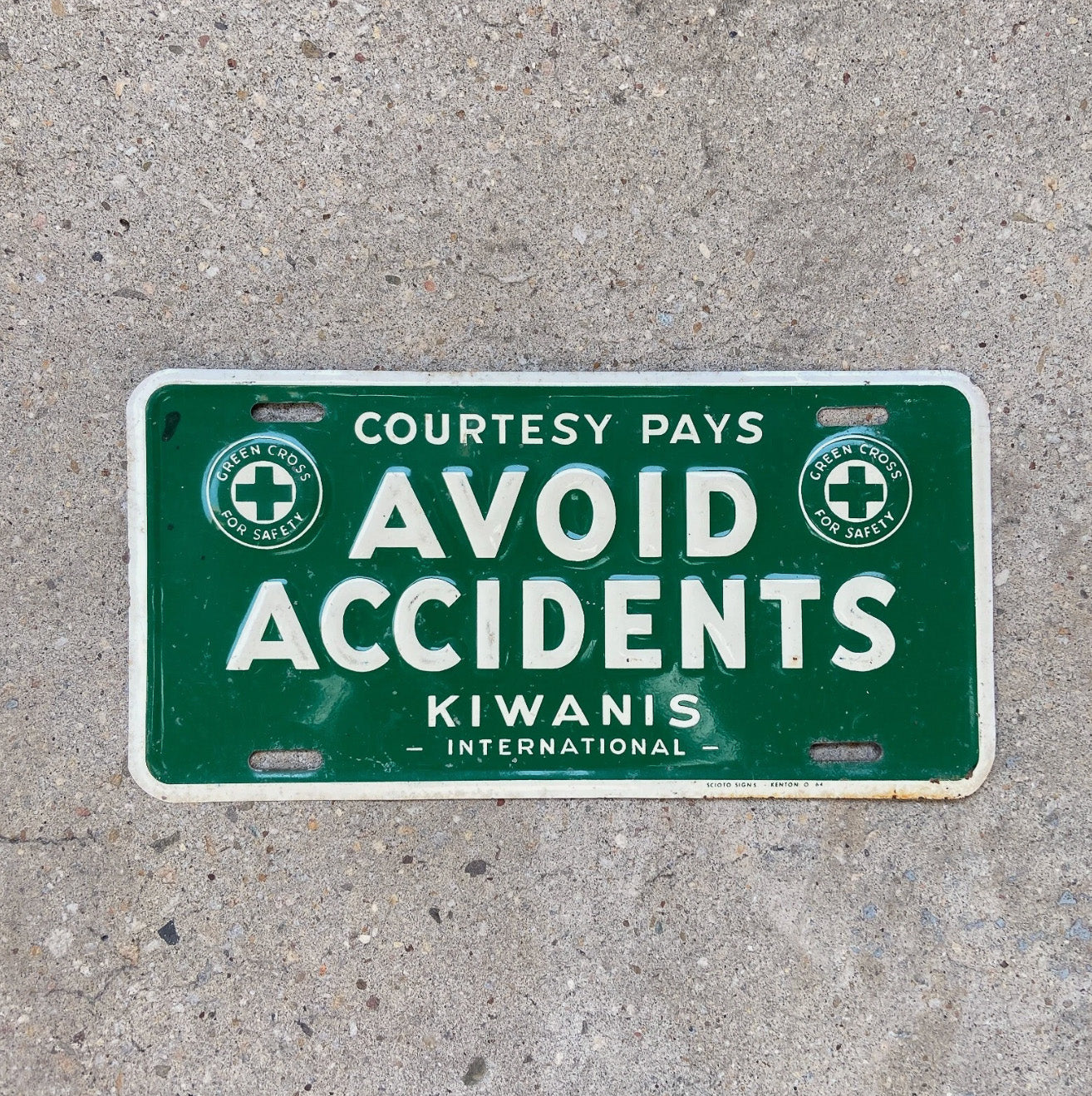 Photo of a 1950 Era Avoid Accidents Booster License Plate Auto Tag 1 Vintage Garage Kiwanis Green Cross with original patina
