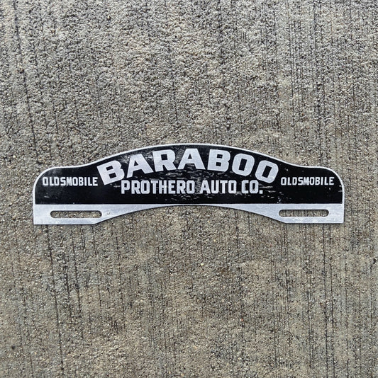 Photo of a 1950 Era Baraboo Wisconsin License Plate Topper Auto Tag Garage Decor Vintage Oldsmobile Dealer Prothero Auto with original patina