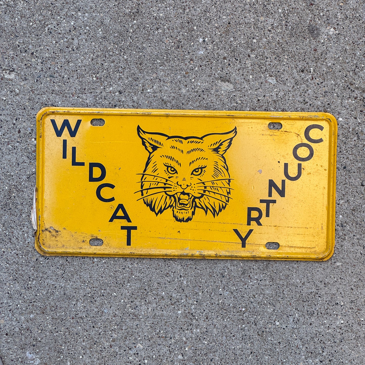Photo of a 1950 Era Booster License Plate Auto Tag Garage Decor New Old Stock with Rice Paper Wildcat Country with original patina
