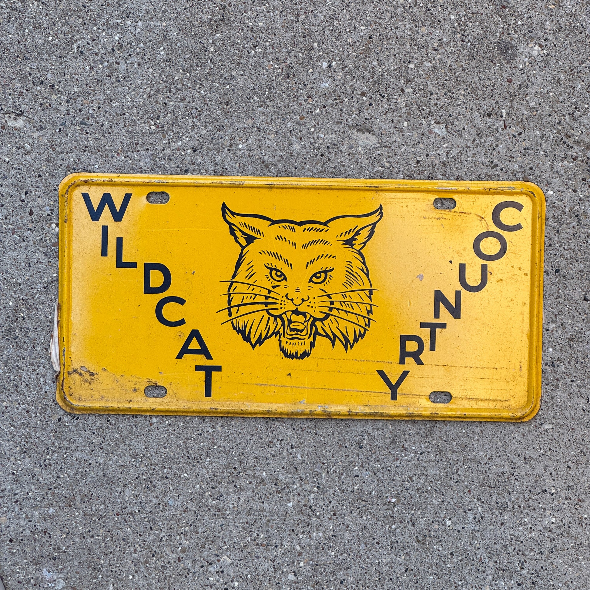 Photo of a 1950 Era Booster License Plate Auto Tag Garage Decor New Old Stock with Rice Paper Wildcat Country with original patina
