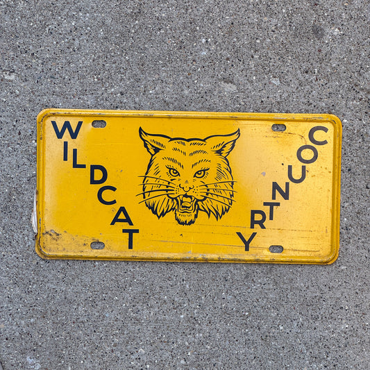 Photo of a 1950 Era Booster License Plate Auto Tag Garage Decor New Old Stock with Rice Paper Wildcat Country with original patina