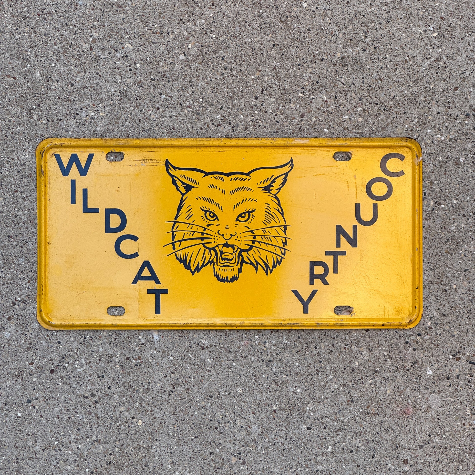 Photo of a 1950 Era Booster License Plate Auto Tag Garage Decor New Old Stock with Rice Paper Wildcat Country with original patina