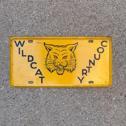 Photo of a 1950 Era Booster License Plate Auto Tag Garage Decor New Old Stock with Rice Paper Wildcat Country with original patina