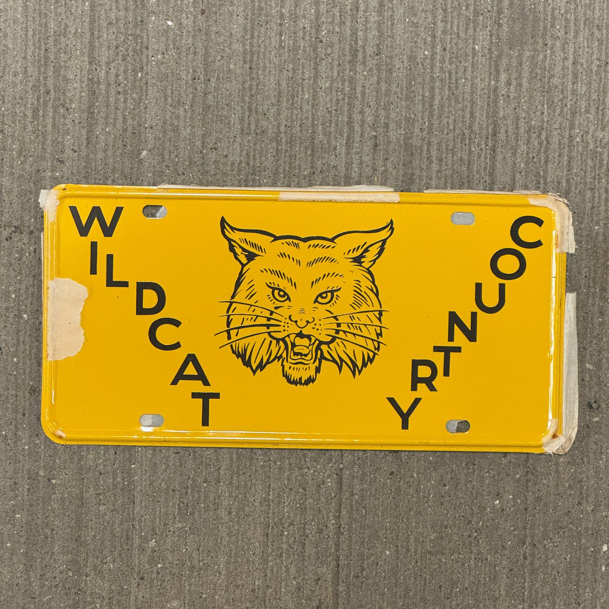 Photo of a 1950 Era Booster License Plate Auto Tag Garage Decor Vintage New Old Stock with Rice Paper Wildcat Country with original patina