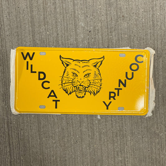 Photo of a 1950 Era Booster License Plate Auto Tag Garage Decor Vintage New Old Stock with Rice Paper Wildcat Country with original patina