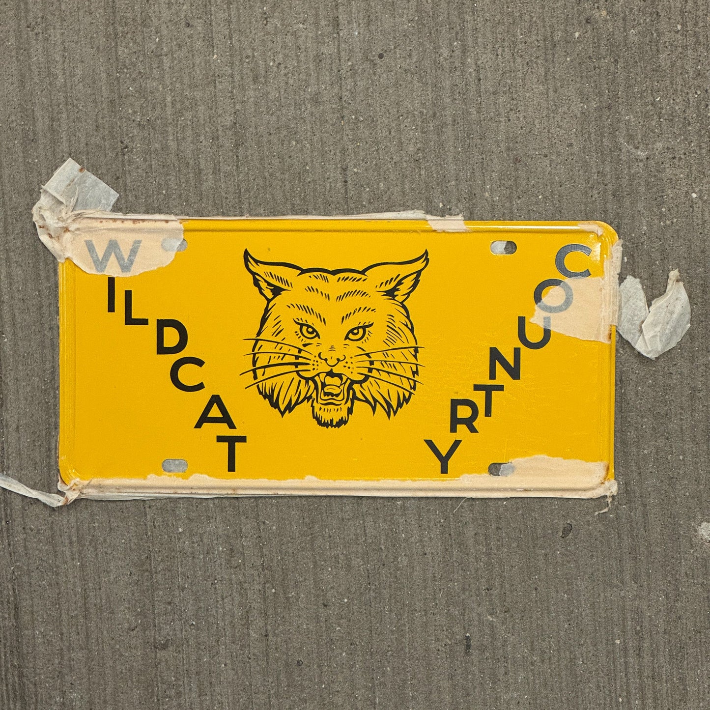 Photo of a 1950 Era Booster License Plate Auto Tag Garage Decor Vintage New Old Stock with Rice Paper Wildcat Country with original patina
