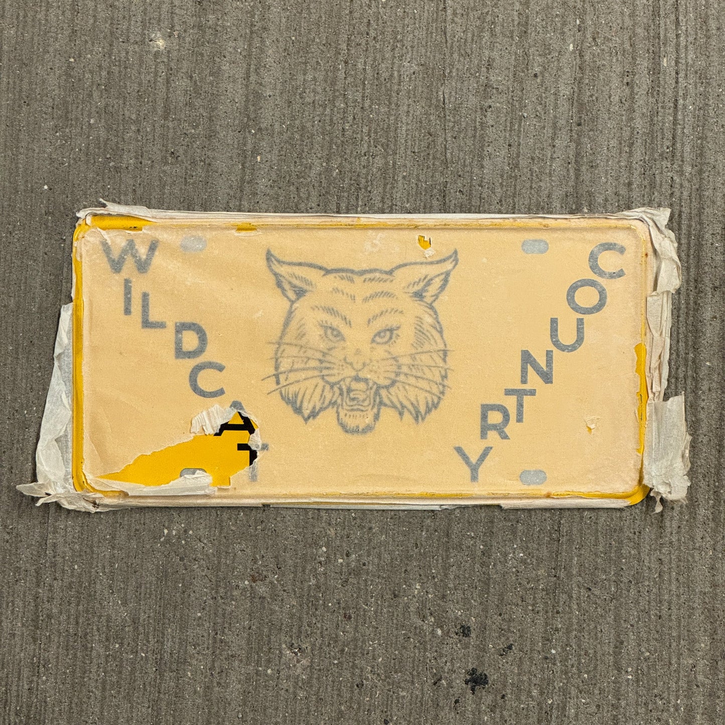 Photo of a 1950 Era Booster License Plate Auto Tag Garage Decor Vintage New Old Stock with Rice Paper Wildcat Country with original patina