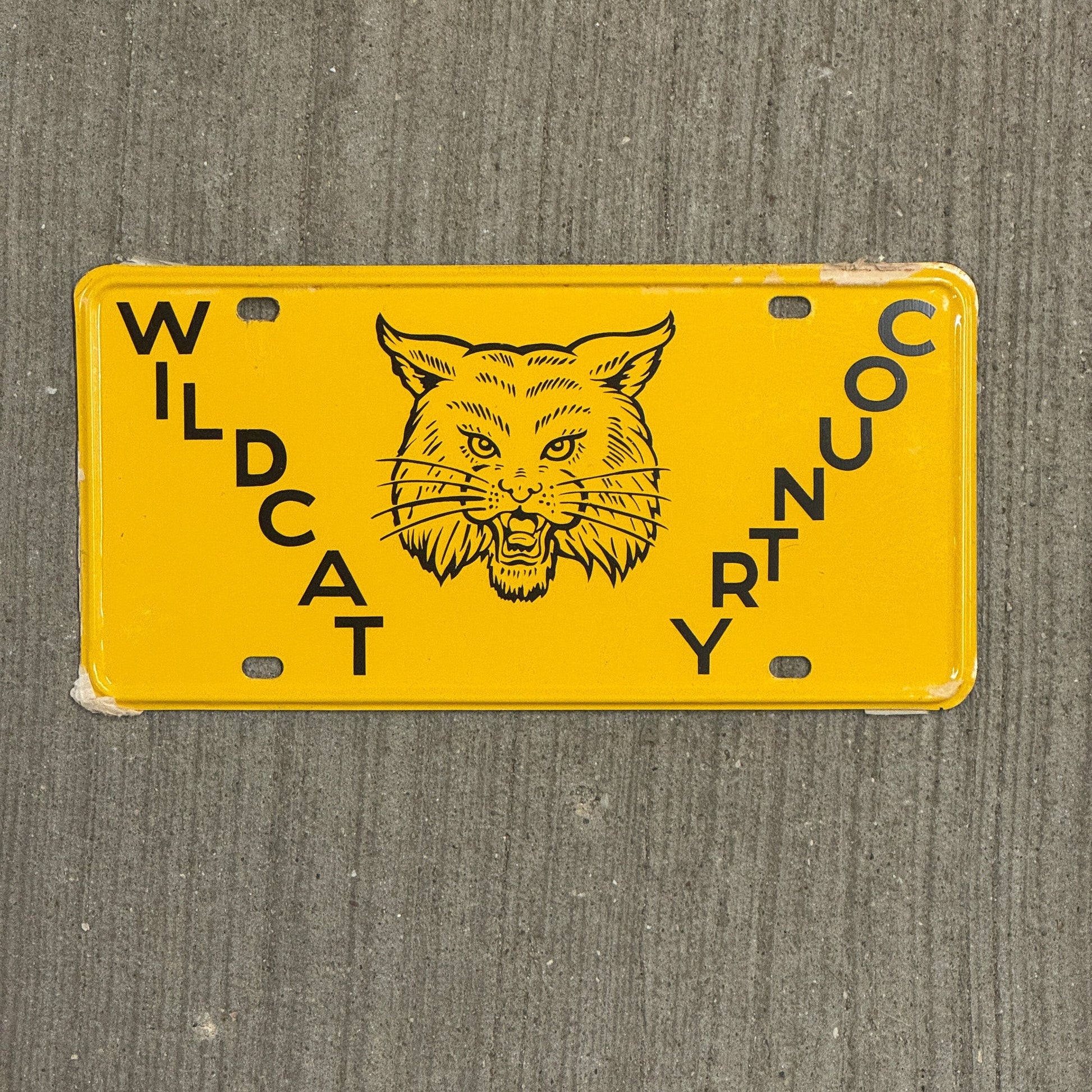 Photo of a 1950 Era Booster License Plate Auto Tag Garage Decor Vintage New Old Stock with Rice Paper Wildcat Country with original patina