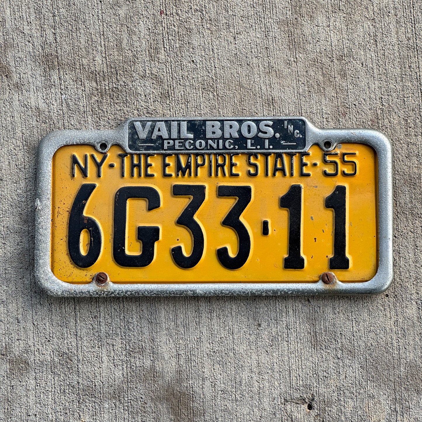 Photo of a 1950 Era Peconic Long Island New York License Plate Frame Auto Tag Garage Decor Vintage Vail Bros Dealer Buick Pontiac Packard with original patina