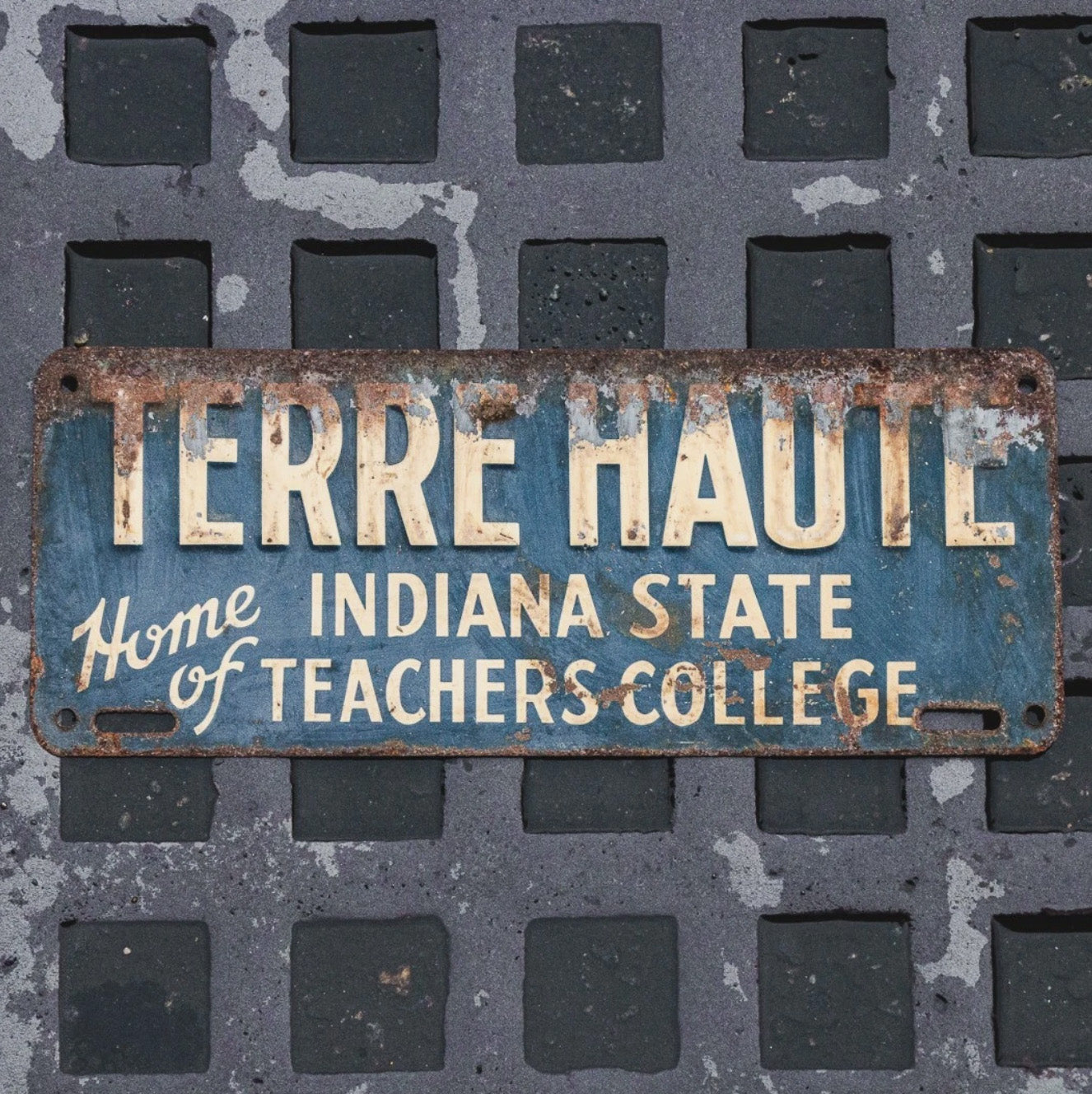 Photo of a 1950 Era Terre Haute Indiana License Plate Topper Auto Tag Garage Decor Vintage IN State Teachers College with original patina