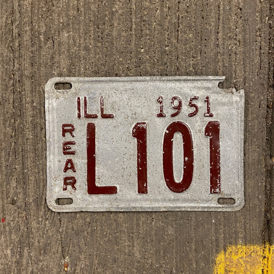 Vintage Illinois truck license plate from 1951 on a concrete background. Registration number L 101.