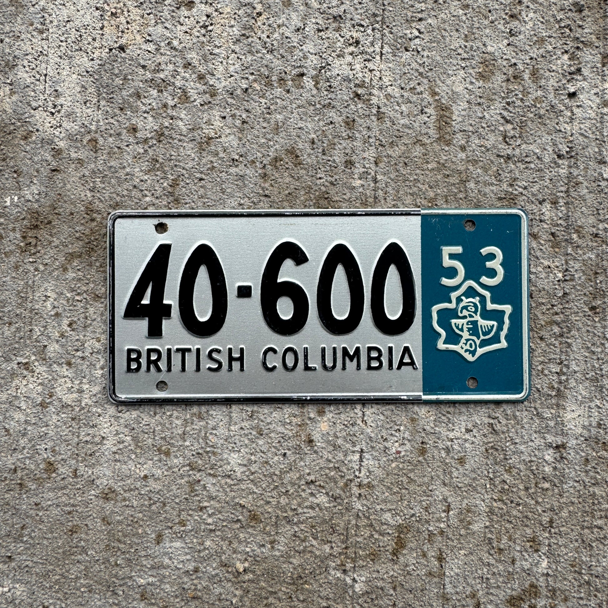 Photo of a 1953 British Columbia Wheaties Cereal Bike License Plate Auto Tag 40-600 on a concrete background