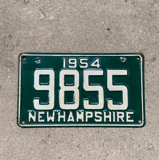 Vintage 1954 New Hampshire license plate with registration number 9855 on a concrete surface