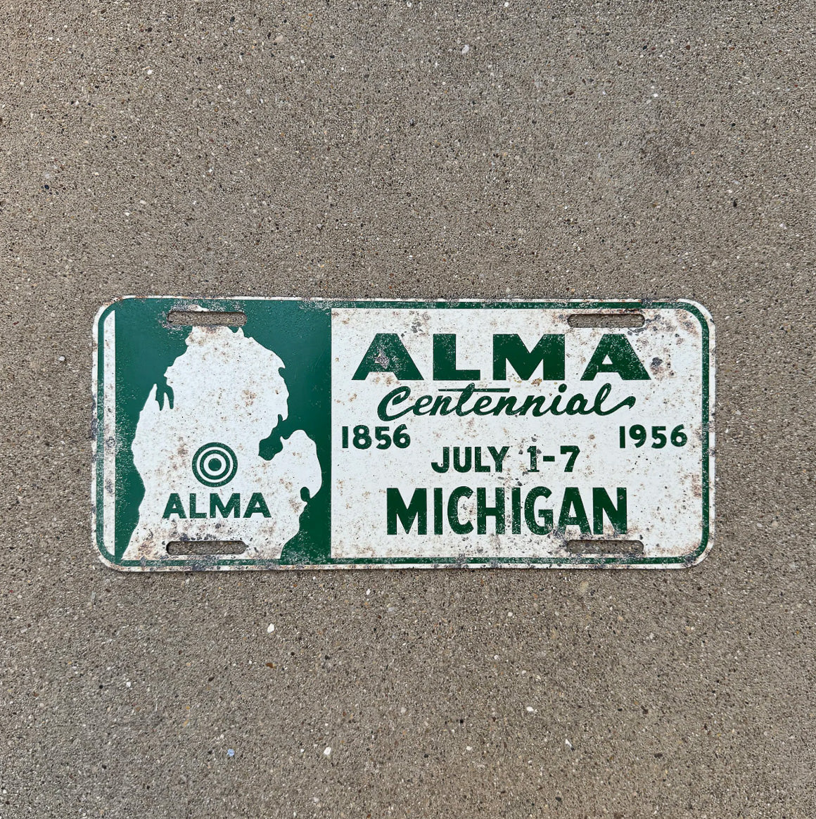 Photo of a 1956 Michigan Booster License Plate Auto Tag Garage Decor Vintage ALMA CENTENNIAL with original patina