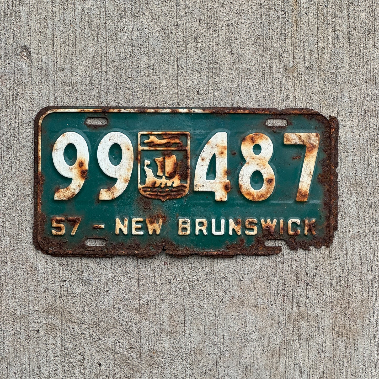 Photo of a 1957 New Brunswick License Plate Auto Tag 1 Vintage Garage Provincial Coat of Arms 99 487 with original patina